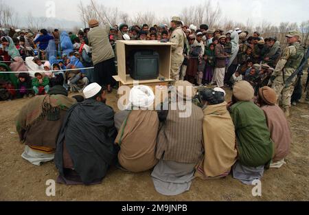 030121-F-7203T-022. [Complete] Scene Caption: A group of local Afghani men from the village of Aroki, located in the Kapisa Province of Afghanistan, prepare to watch a video entitled 'Why We Are Here' which explains the US Military involvement in the war on terrorism during a Medical Civil Action Program (MEDCAP) held in their village. US Army (USA) Soldiers from the 48th Combat Support Hospital, along side US Air Force (USAF) Airmen from the 455th Air Expeditionary Wing (EAW) and Republic of Korea (ROK) Army Soldiers from the 924th Medical hospital, operate the programs, which provides free m Stock Photo