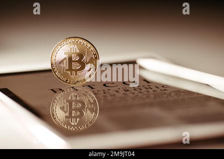 A closeup shot of a Bitcoin lying on a newspaper about cash system Stock Photo