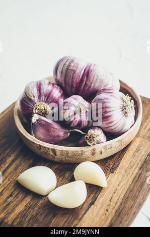 Rustic style garlic on vintage wooden background. Fresh young peeled purple garlic. Stock Photo