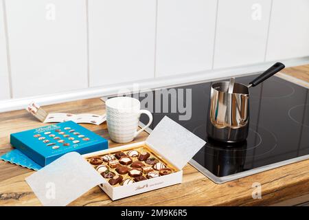 Zurich, Switzerland - January, 7 2023: Lindt Mini Pralines Box. Open small gift box of Swiss chocolate candies ready for coffee at kitchen. Luxurious selection of milk, dark and white sweets. Stock Photo