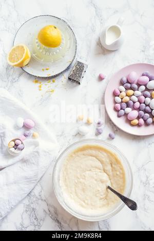 Process of preparation Easter pastry cake or cupcakes decorated with mini chocolate eggs candy on white marble background. Easter baking concept. Top Stock Photo