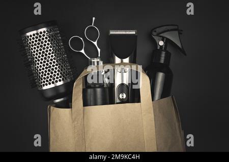 Composition with scissors, other hairdresser's accessories in a craft package on black background Stock Photo