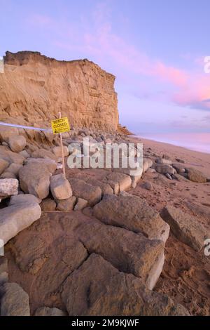 West Bay, Bridport, Dorset, UK. 18th Jan, 2023. UK Weather: The beach at the seaside resort of West Bay was closed today following a large landslip. A large pile of rocks could be seen on the beach leaving a scar in the cliff face made famous by the TV drama series Broadchurch. The honeycombe coloured rocks along this part of the Jurassic coast are known locally as being dangerous and prone to coastal erosion. Credit: Celia McMahon/Alamy Live News Stock Photo