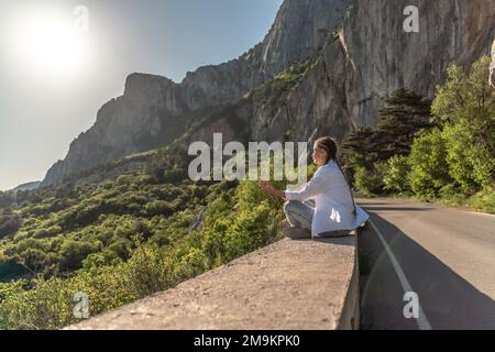 Profile of a woman doing yoga in the top of a cliff in the mountain. Woman meditates in yoga asana Padmasana Stock Photo