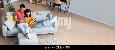 Wide Extended Banner With Happy Asian Couple Relaxing Together At Home Stock Photo