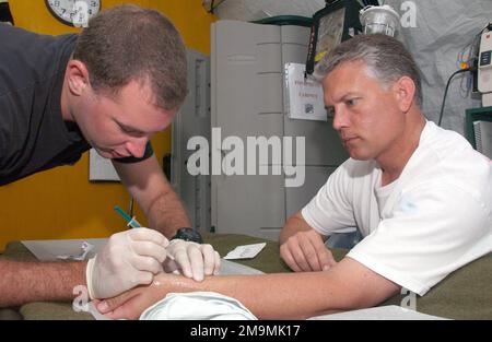 US Air Force (USAF) STAFF Sergeant (SSGT) Zachary King (left), Cardiovascular Technician, 40th Expeditionary Medical Squadron (EMDS), draws blood from USAF Captain (CAPT) Daniel Park to get a reading on his blood gas levels during Operation IRAQI FREEDOM. Subject Operation/Series: IRAQI FREEDOM Country: Unknown Stock Photo