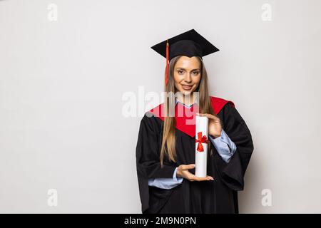 Attractive woman wearing a graduation gown and looking at the camera with her arms crossed. Smart woman smiling and graduating from university Stock Photo