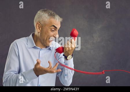 Middle-aged man talk on telephone isolated on black background Stock Photo