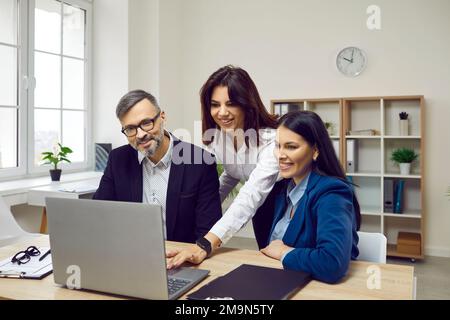 Group of confident business people analyzing data using laptop Stock Photo