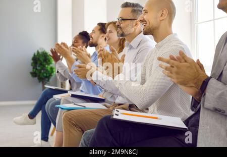 Happy audience sitting in row at professional business seminar, applauding and smiling Stock Photo