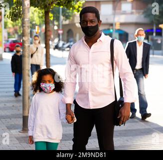 african father and daughter in masks on street Stock Photo