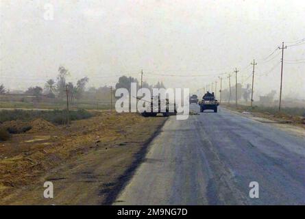 US Marine Corps (USMC) Light Armored Vehicles (LAV-25) assigned to Delta/Company, 1ST Light Armored Reconnaissance Battalion (LARB), 1ST Marine Division, pass a partially destroyed abandoned Iraqi T-55 Main Battle Tank (MBT), sitting along a roadside in Northern Iraq, during Operation IRAQI FREEDOM. (Substandard image). Subject Operation/Series: IRAQI FREEDOM Country: Iraq (IRQ) Stock Photo