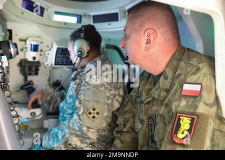 Polish army Warrant Officer 4 Robert Sagatowski observes as U.S. Army Staff Sgt. Chantey Fryer, assigned to the 1st Battalion, 68th Armor Regiment, 3rd Armored Brigade Combat Team, 4th Infantry Division, shows him the various instruments within the Advanced Gunnery Training System tank simulator during the next phase of the Tank Academy, the Abrams Apprenticeship Program at Konotop, Drawsko Pomorskie, Poland, May 20, 2022. The 3/4 ABCT is among other units assigned to the 1st Infantry Division, proudly working alongside NATO allies and regional security partners to provide combat-credible forc Stock Photo