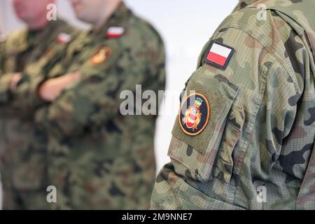 A Polish flag and unit crest on the arm of a group of Polish soldiers as they listen to a classroom portion taught by U.S. Army Sgt. 1st Class Darren Brinson, a master gunner assigned to 1st Battalion, 68th Armor Regiment, 3rd Armored Brigade Combat Team, 4th Infantry Division, during the next phase of the Tank Academy, the Abrams Apprenticeship Program at Konotop, Drawsko Pomorskie, Poland, May 20, 2022. The 3/4 ABCT is among other units assigned to the 1st Infantry Division, proudly working alongside NATO allies and regional security partners to provide combat-credible forces to V Corps, Ame Stock Photo