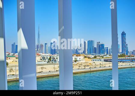 DUBAI, UAE - MARCH 6, 2020: The view on Dubai Water Canal and modern city towers through the white elements of Water Canal Footbridge, on March 6 in D Stock Photo