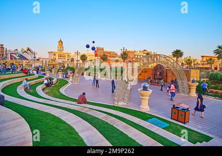 DUBAI, UAE - MARCH 6, 2020: Evening in topiary park of Global Village Dubai with green lawn, flower beds, illuminated arches and trade pavilions in ba Stock Photo