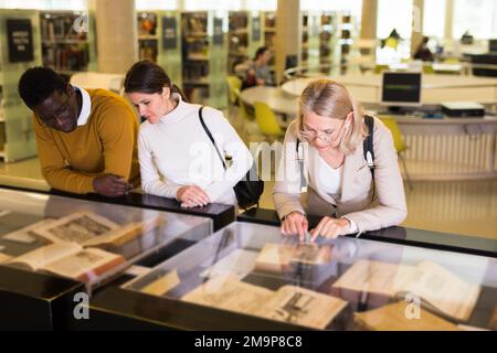 Professor and adult students read ancient books in a library showcase Stock Photo