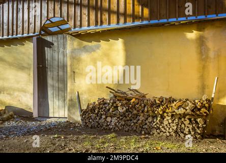 A pile of stacked firewood, prepared for heating the house, harvested for heating in winter on the house wall Stock Photo