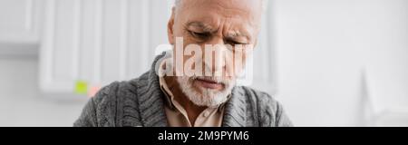depressed grey haired man with alzheimer syndrome looking down at home, banner,stock image Stock Photo
