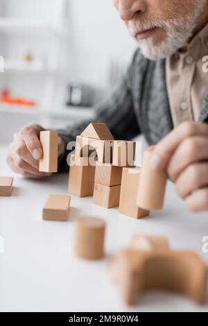 partial view of man with alzheimer disease playing building blocks game on blurred foreground,stock image Stock Photo