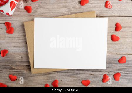 Valentines day card, blank invitation stationery card mockup with envelope and red hearts on wooden background, top view Stock Photo