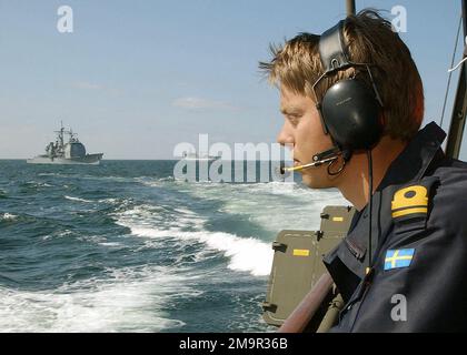 030613-N-4374S-014. [Complete] Scene Caption: A Swedish Royal Navy Sub Lieutenant assigned to Fast Attack Craft HMS NORRKOPING (R 131), observes the US Navy (USN) Aegis Class Guided Missile Cruiser USS VELLA GULF (CG 72) (left) and the German Navy Oiler FGS RHOEN (A 1443) on the Baltic Sea, during the annual maritime Exercise BALTIC OPERATIONS 2003 (BALTOPS). The United States and 12 other nations are participating in this year's exercise. BALTOPS 2003 is intended to improve interoperability between allies and Partnership for Peace countries by conducting support operations at sea including ex Stock Photo