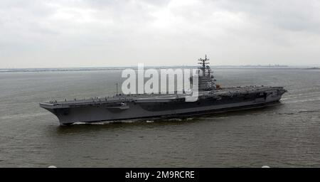 Port bow view of the US Navy (USN) Nimitz class Nuclear-powered Aircraft Carrier USS RONALD REAGAN (CVN 76) leaves port for the first time as a commissioned naval vessel. The weather conditions are dark, cloudy and overcast. Base: Hampton Roadstead State: Virginia (VA) Country: United States Of America (USA) Stock Photo