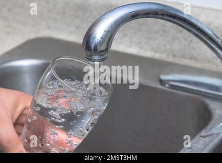Pouring water into a glass. Filling glass with drinkable water. Stock Photo