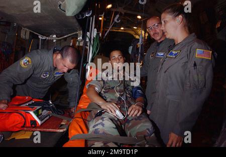030915-F-3838S-011. [Complete] Scene Caption: US Air Force (USAF) Captain (CPT) David Delang (right center), Doctor, 86th Aeromedical Evacuation Squadron (AES), Ramstein Air Base (AB), Germany, monitors as sensors from a heart and lung monitor are applied to US Marine Corps (USMC) Corporal (CPL) Antwone Boyd, 26th Marine Expeditionary Unit (MEU). USAF CPT Delang is treating USMC CPL Boyd for Malaria aboard a USAF C-130 Hercules, 123rd Airlift Wing (AW), Louisville, Kentucky (KY), during a medical evacuation (MEDEVAC) from Liberia to Naval Air Station (NAS) Rota, Spain, during JOINT TASK FORCE Stock Photo
