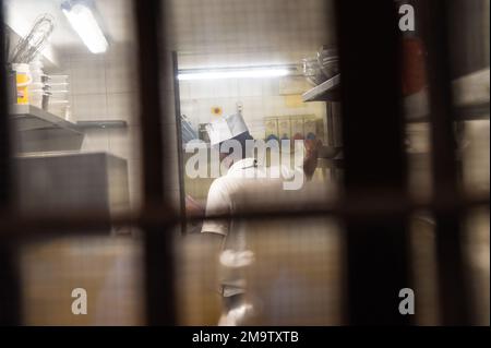 A view from a back alley on a street near the Piazzo San Marco, Venice into a restaurant with a cook working in the kitchen. Stock Photo