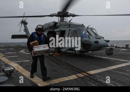 220520-N-ED646-0150 BALTIC SEA (May 20, 2022) Boatswain's Mate Seaman Orion Spragg carries packages from an MH-60S Sea Hawk helicopter, assigned to the 'Street Dogs' of Helicopter Sea Combat Squadron (HSC) 28, on the flight deck aboard the Arleigh Burke-class guided-missile destroyer USS Gravely (DDG 107) during flight quarters in the Baltic Sea, May 20, 2022. Gravely is on a scheduled deployment in the U.S. Naval Forces Europe area of operations, employed by U.S. Sixth Fleet to defend U.S., allied and partner interests. Stock Photo