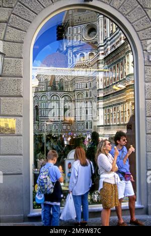 Family enjoying gelato while admiring the Duomo which is reflected in a shop window in the streets of Florence, Italy. Stock Photo