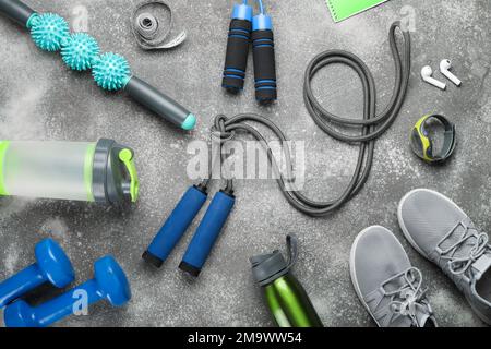Skipping ropes with sports equipment, bottles, measuring tape and sneakers on dark background Stock Photo