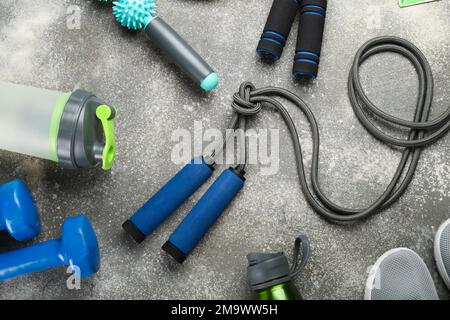 Skipping ropes with sports equipment, bottles and sneakers on dark background Stock Photo
