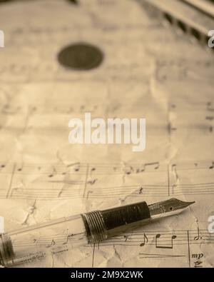 A Harmonica copper coin and fountain pen on an old paper vintage music sheet Stock Photo