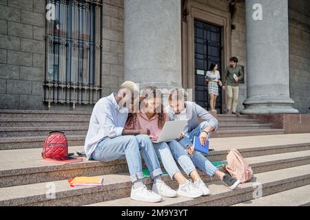student friends discussing internet news while sitting on the steps. technology, education, youth. Stock Photo