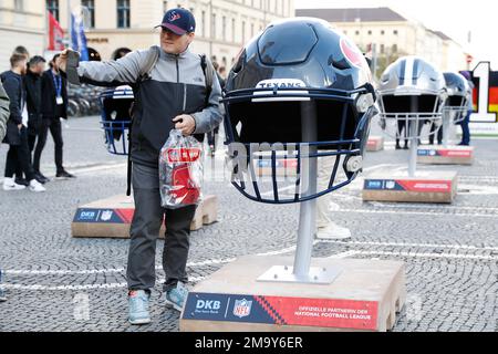 A fan poses with a large Atlanta Falcons helmet at an NFL fan activation at  Odeonsplatz in Munich, Germany, Saturday, Nov. 12, 2022. The Tampa Bay  Buccaneers will take on the Seattle