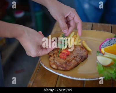 Chefs hand prepares a Grilled pork ribs  and decorates  hearb Stock Photo