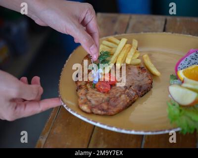 Chefs hand prepares a Grilled pork ribs  and decorates  flowers. Stock Photo