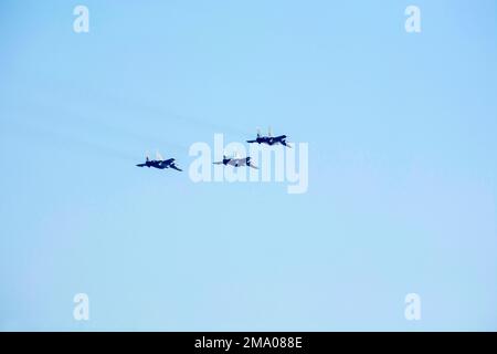 Flying aircraft with Vic formation against isolated blue sky. Three supersonic fighter plane forming Arrowhead. Stock Photo