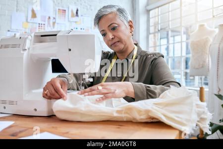Tailor, senior woman and sewing machine for clothes fabric, luxury apparel or creative design in studio workshop atelier. Startup small business Stock Photo