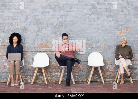 Business people, waiting room and sitting on chairs against brick wall for interview, meeting or opportunity. Group of creative interns in social Stock Photo