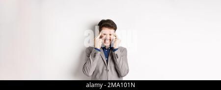Image of frustrated man trying to think, cant remember something, touching head temples and squinting with tensed grimace, brainstorming, searching Stock Photo