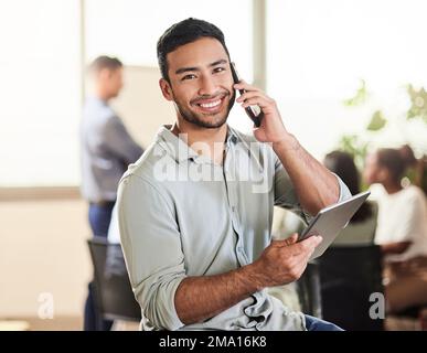 Im so glad you got back to me. a young businessman using his smartphone to make a phone call while holding his digital tablet. Stock Photo