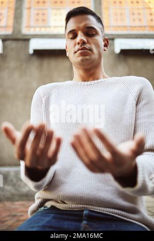 Pray, muslim man and sitting person in a mosque for holy temple worship and prayer for ramadan. Islamic, young male and praying of a guy with faith Stock Photo