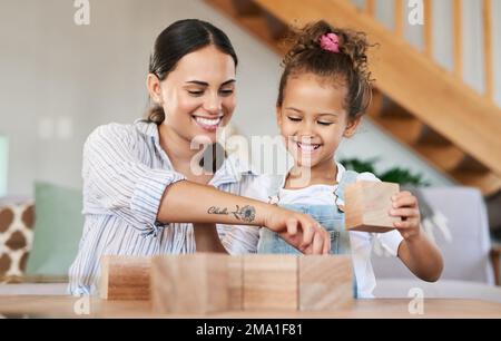 Lets build something cool together. a mother and her daughter playing with wooden blocks together at home. Stock Photo