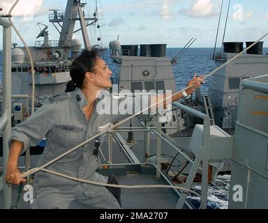 Royal Australian Navy (RAN) Able SEAMAN, Communications SPECIALIST, Natalie Haumu, retrieves a signal flag, aboard the RAN DURANCE CLASS: Underway Replenishment Tanker, Her Majestys Australian Ship (HMAS) SUCCESS (OR 304), as the ship begins a Refuel At Sea (RAS) operation with the US Navy (USN) ARLEIGH BURKE CLASS: (Flight I), Guided Missile Destroyer, USS JOHN PAUL JONES (DDG 53) (underway background), while participating in Exercise RIMPAC 2004. RIMPAC is the largest international maritime exercise conducted in the waters around the Hawaiian Islands, and is designed to enhance the tactical Stock Photo