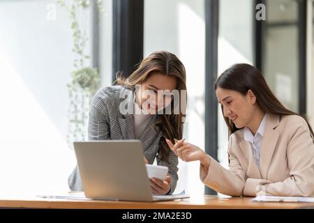 Young colleagues discuss business and analytical price charts using calculators and laptops to calculate financial, tax, accounting, statistics and Stock Photo