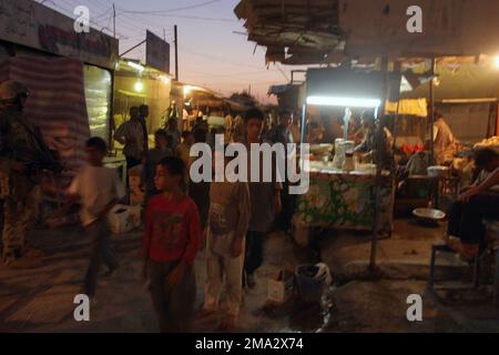 Local Iraqis watch US Marine Corps (USMC) Marines, Lima Company (L Co), 3rd Battalion (BN), 1ST Marine Division (MARDIV), conduct a raid at dusk in the market area of Nassir Wa Al Salam, Iraq. The 1 MARDIV is engaged in a Security and Stabilization Operation (SASO) in the Al Anbar Province during Operation IRAQI FREEDOM. Base: Nassir Wa Al Salam State: Al Anbar Country: Iraq (IRQ) Stock Photo