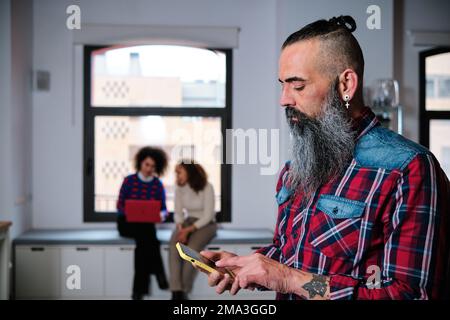 Man using mobile phone while standing in coworking office. Stock Photo